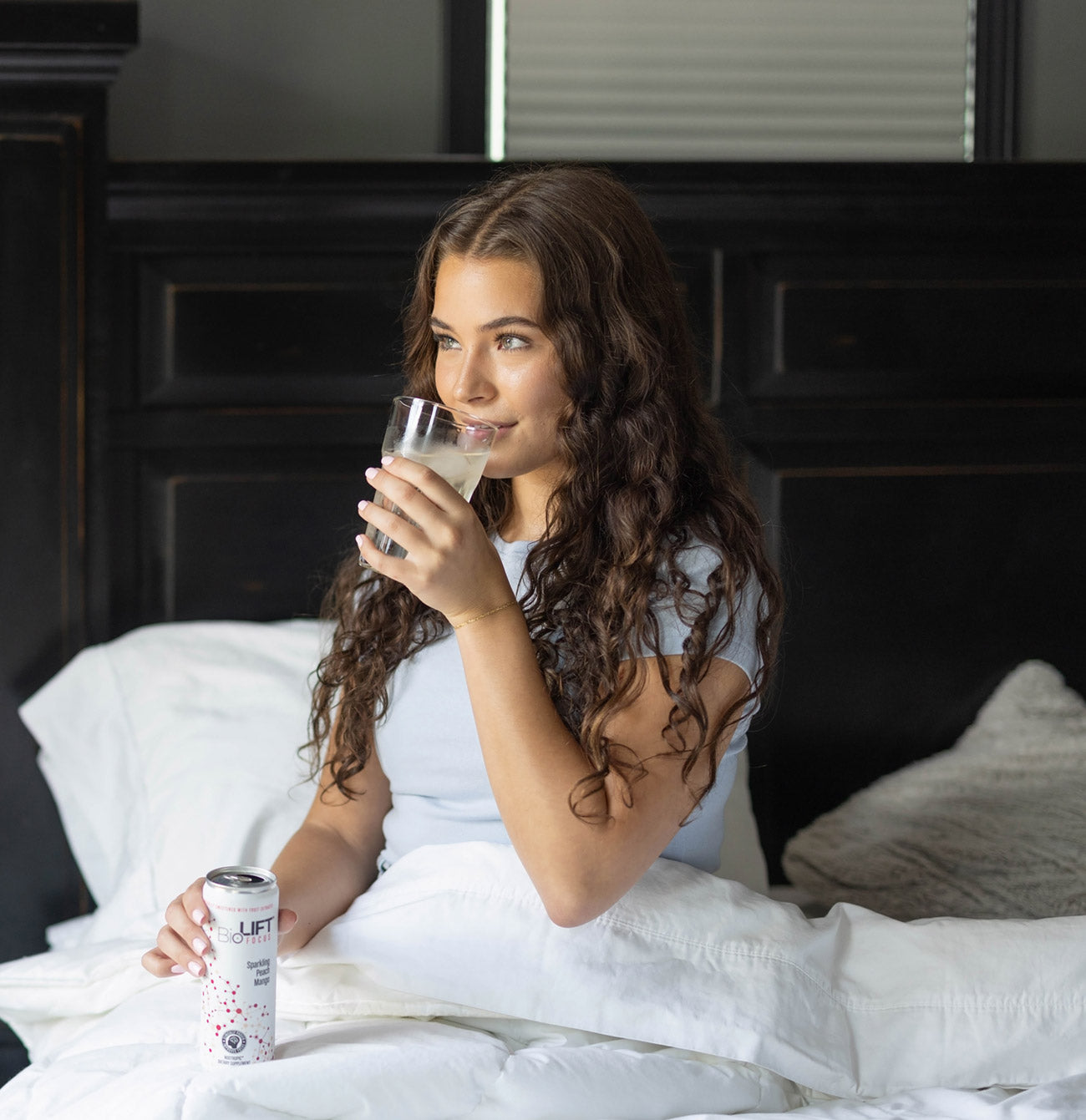 Woman waking up in bed drinking BioLift